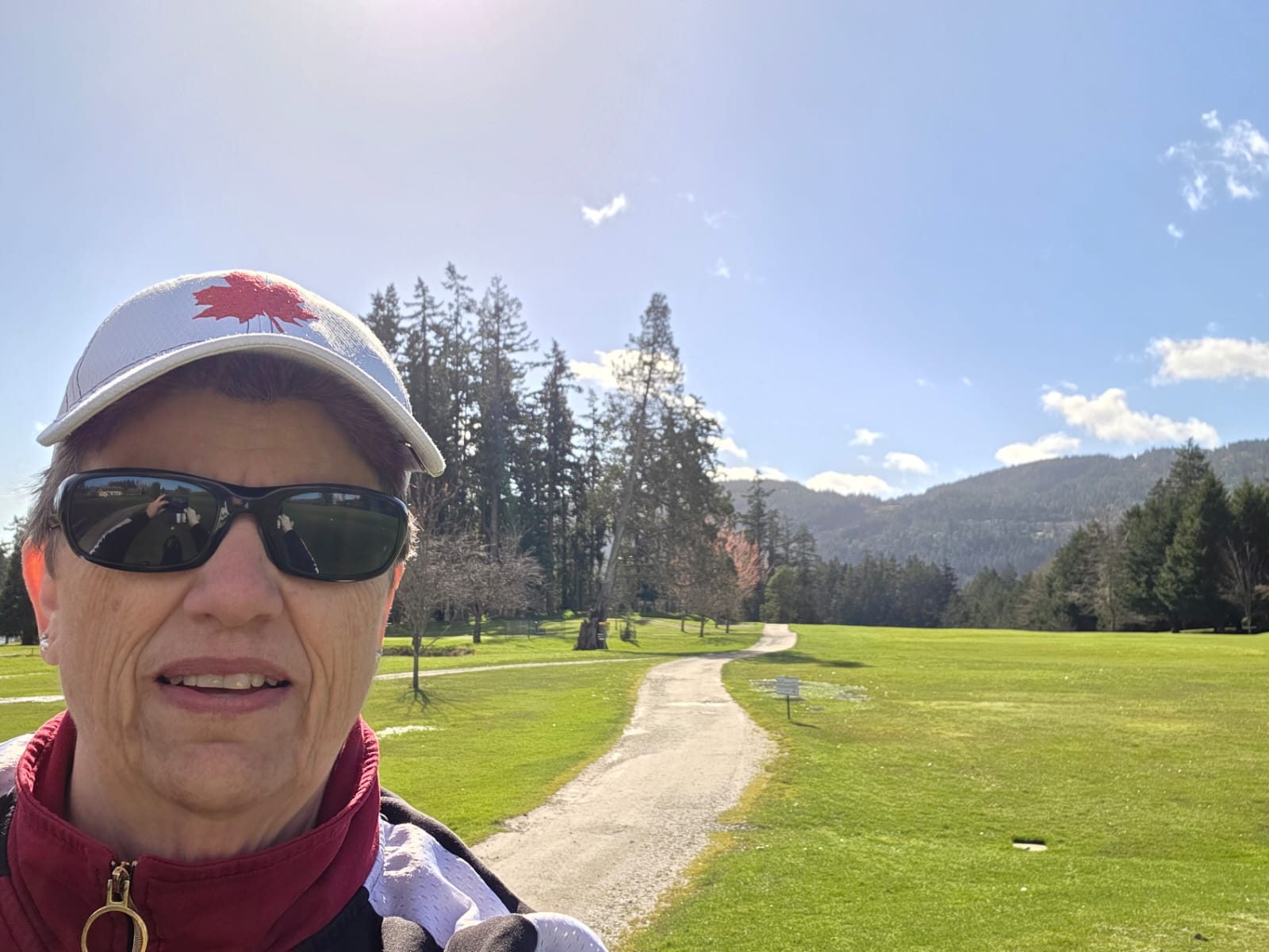 Lori Danecke on the golf course, fairway and mountains behind her